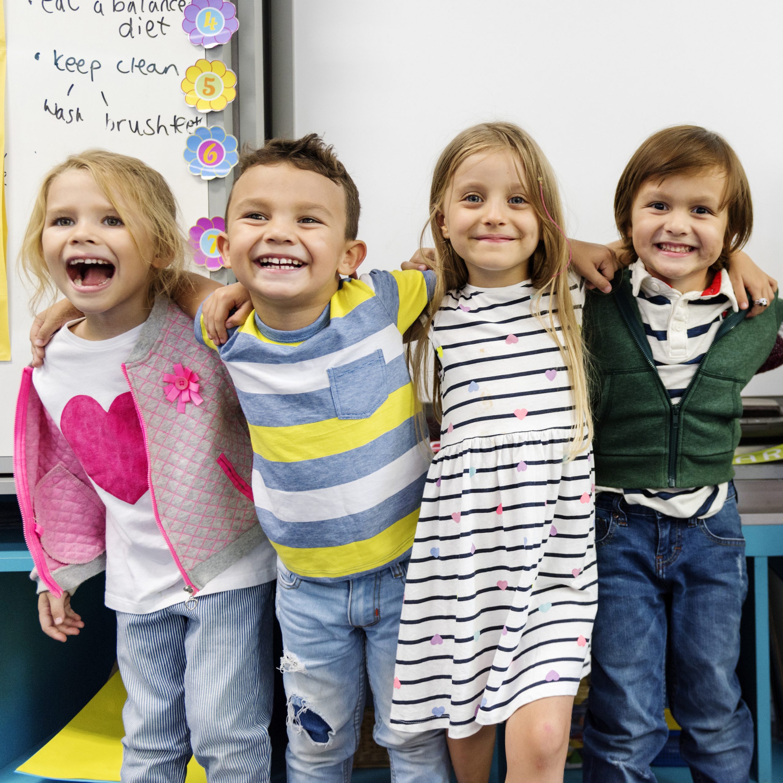 Group of diverse kindergarten students standing together in clas